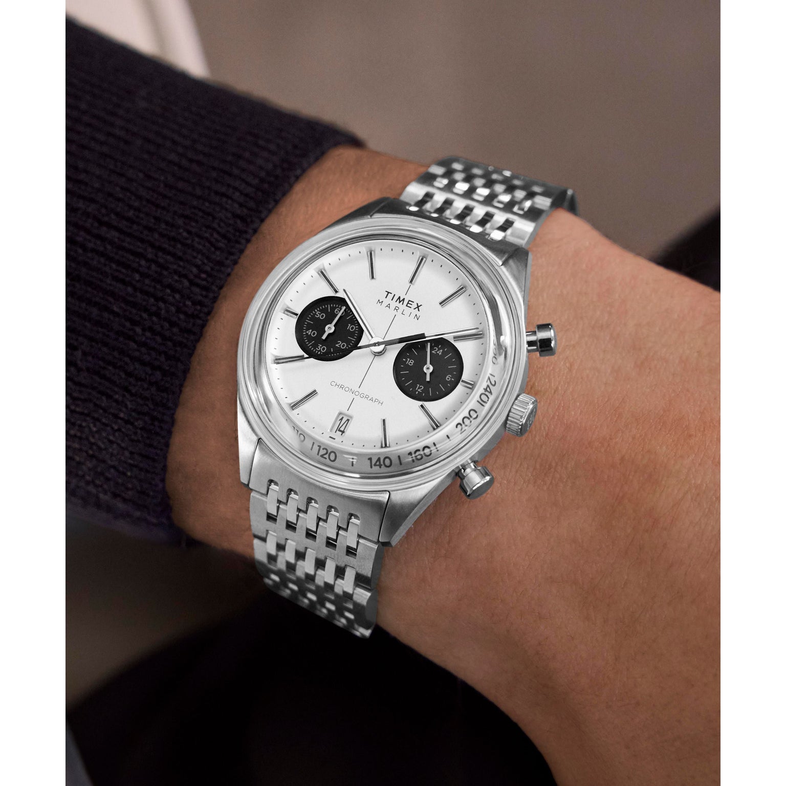 A close-up of a wrist wearing the Timex Marlin® Jet Quartz Chronograph with a white dial, two black subdials, and a metal bracelet, paired with a dark long-sleeve shirt—a true retro-futuristic statement.