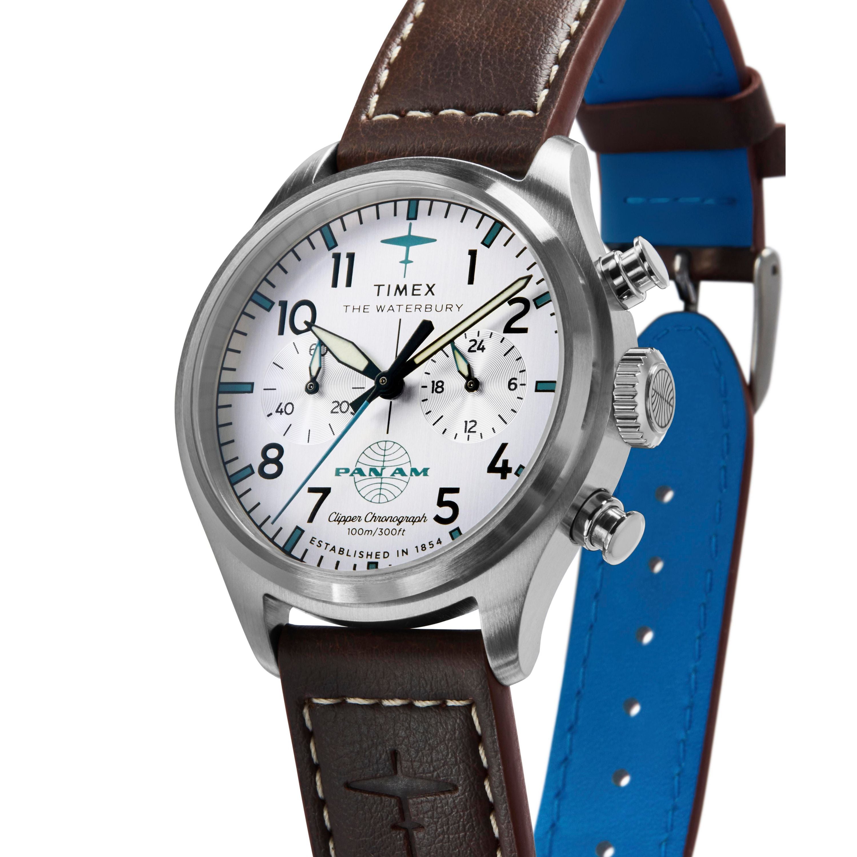 The Timex G SS QZ SW WATERBURY TRAD 41 WHITE DL 25 features a stainless-steel case, white dial with black numerals, chronograph, brown leather strap with blue underside and embossed airplane, plus Pan Am logo and text on the face.