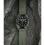 The Timex Expedition® Capstone Automatic wristwatch, with a green fabric strap and black dial with luminous numbers, powered by Japanese automatic movement, is displayed on textured gray rocks.