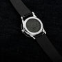 Watch with black strap and visible brand name on a dark textured background