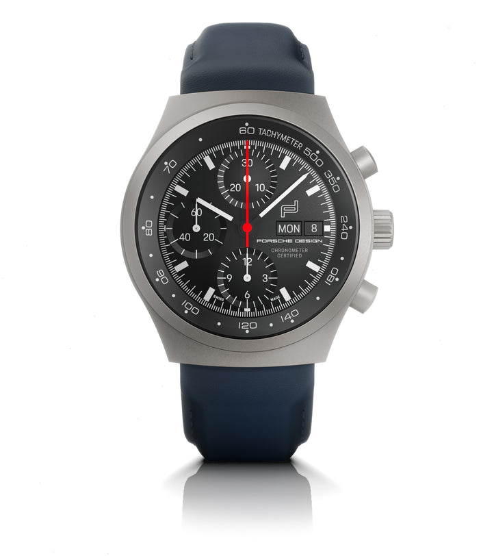 Titanium chronograph watch with black dial, tachymeter bezel, date window, and dark blue rubber strap.