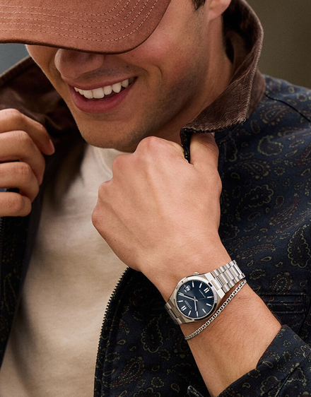 Man wearing a watch with a brown cap and patterned jacket