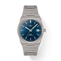 The Tissot PRX 38 is a stainless steel automatic watch featuring a blue textured dial, silver markers, date at 3 o’clock, 80-hour power reserve, and a silver link bracelet displayed on a white background.