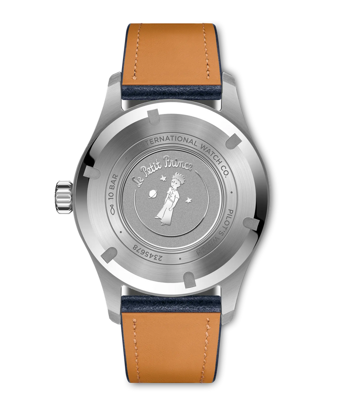 Steel pilot's watch with round face, tan and navy leather strap, Le Petit Prince illustration on caseback.