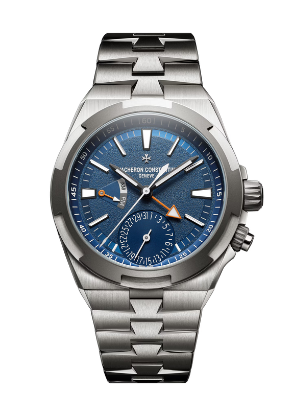 Stainless steel watch with blue dial, dual time zone subdial, orange triangular hand, and brushed metal bracelet.