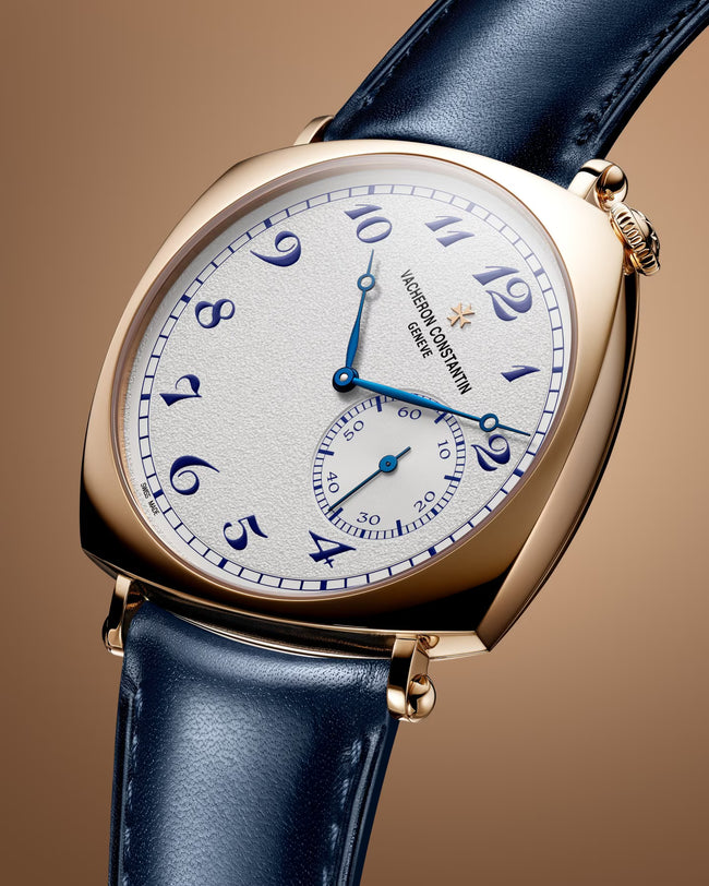 Gold-tone watch with white dial, blue Arabic numerals, blue hands, and dark blue leather strap.