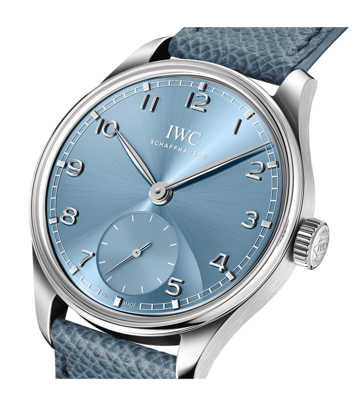 A close-up of the IWC Schaffhausen Portugieser Automatic 40 reveals its metallic blue dial, silver hands, Arabic numerals, a sub-dial at 6 o’clock, and a textured blue leather strap in polished stainless steel.