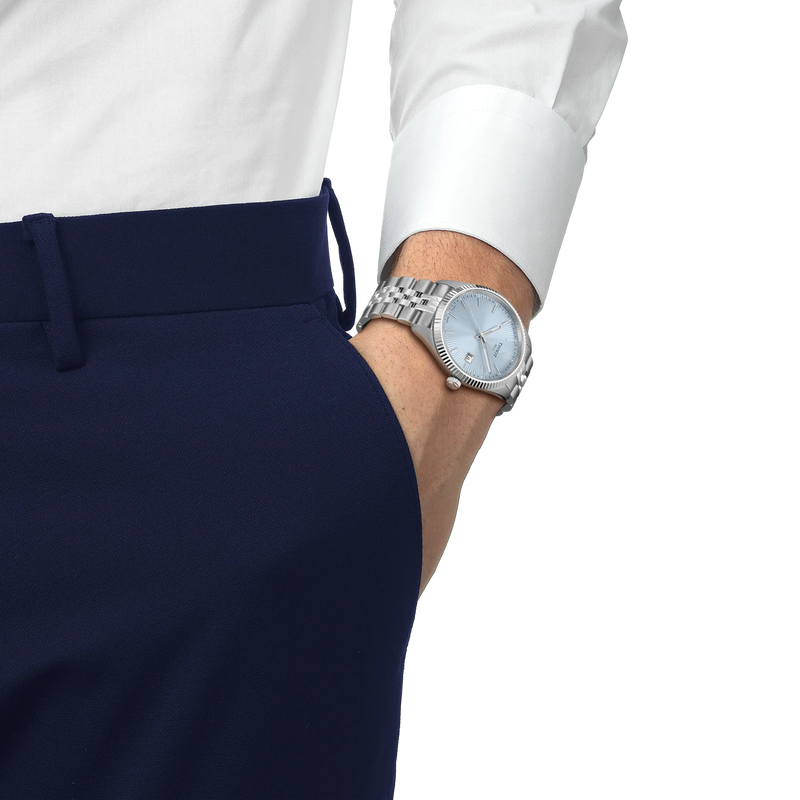 Silver watch on a wrist with a white shirt and navy pants against a white background
