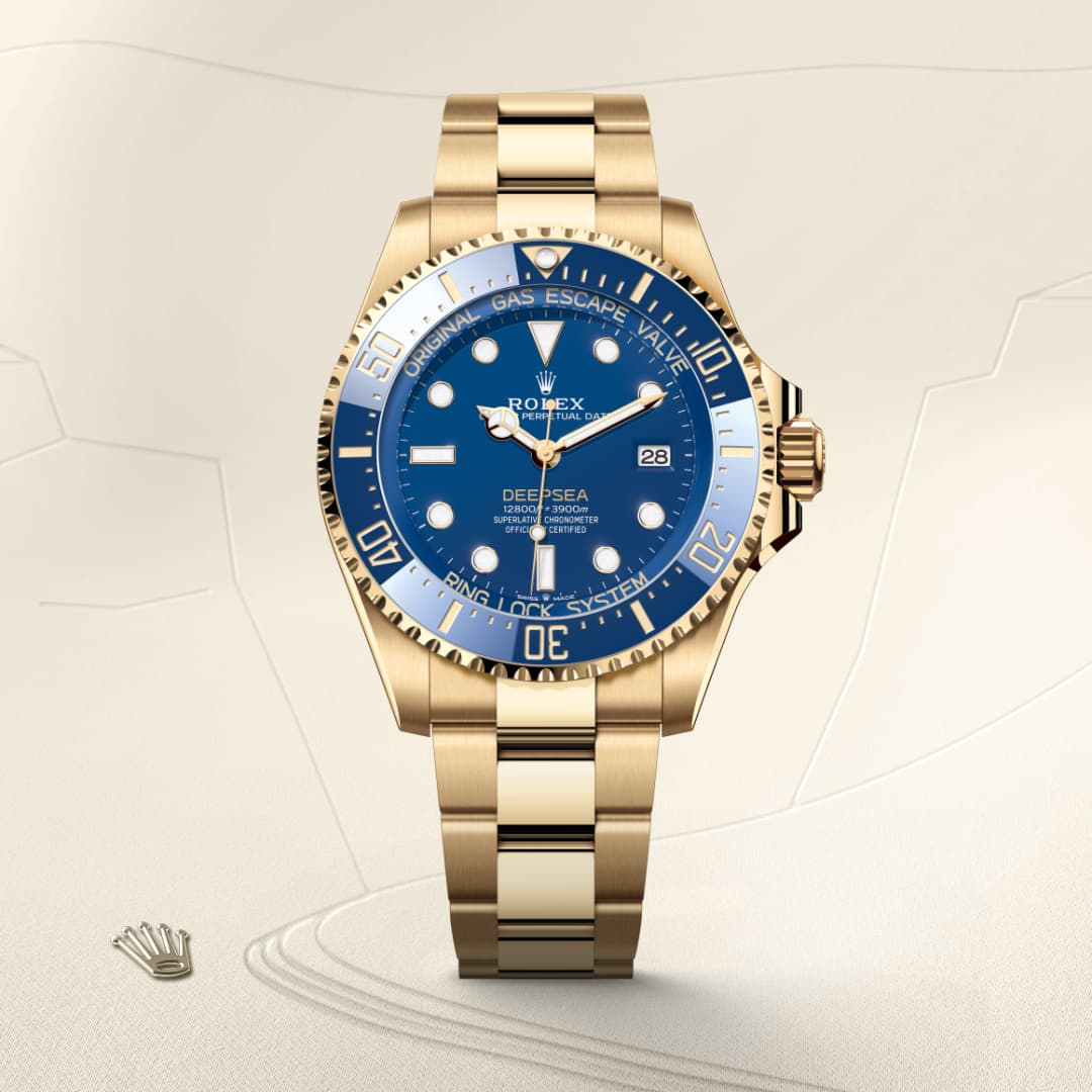 A gold Rolex Deepsea watch with a blue gradient dial displayed on a light, textured background.