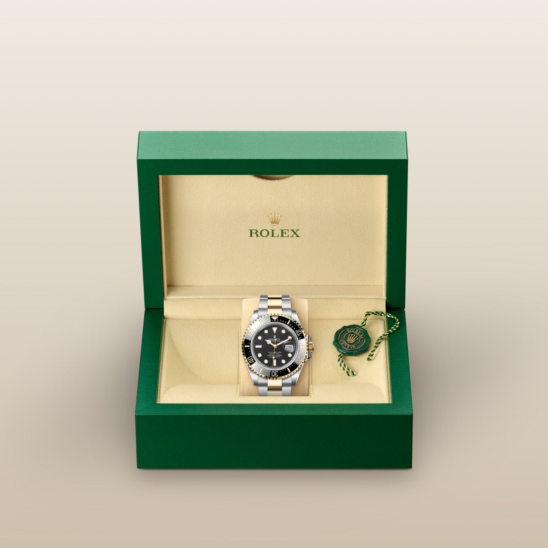 A Rolex watch with a black dial in a green and beige box, accompanied by a green and gold tag.