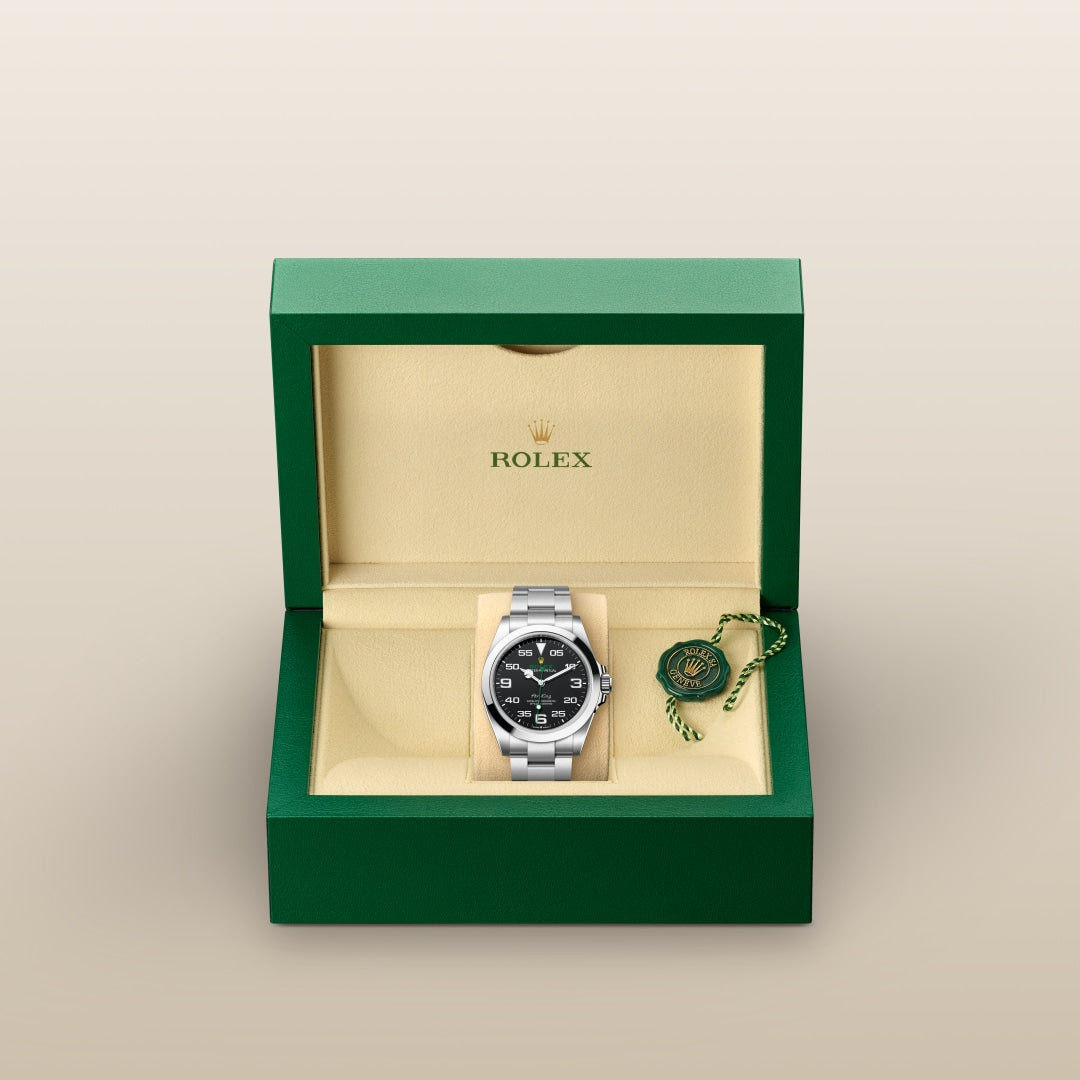 A Rolex watch with a black dial in a green and beige box, accompanied by a green and gold tag.