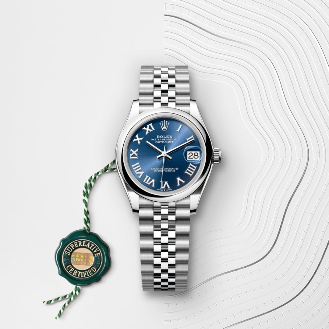 A Rolex watch with a blue dial, silver bracelet, date display, and a green “Superlative Certified” tag.