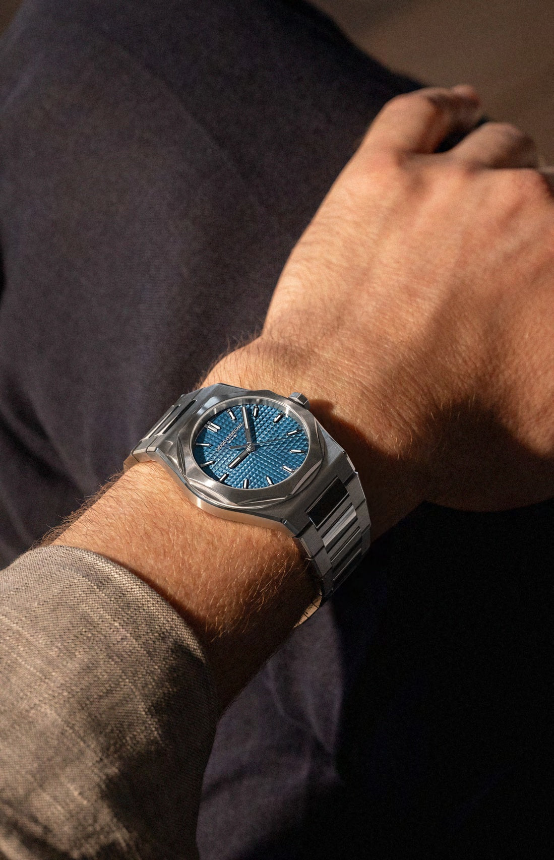 Close-up of a person's wrist wearing a silver watch with a blue face.