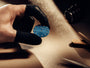 Hand holding a blue circular object with a textured surface on a wooden surface.