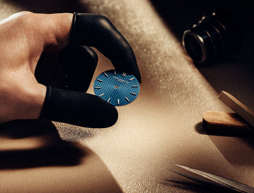 Hand holding a blue circular object with a textured surface on a wooden surface.