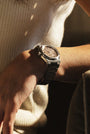Close-up of a person's wrist wearing a silver watch with a blurred background