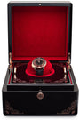 Black watch winder box with red velvet interior displaying tourbillon watch with roulette wheel dial on red cushion.