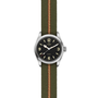 The TUDOR Ranger is a stainless steel expedition watch with a black dial, bold luminescent numerals, and simple hour, minute, and second hands. It comes on a green fabric strap featuring a central red and beige stripe.