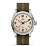 The TUDOR Ranger is an expedition watch with a beige dial, bold black numerals and hands, a stainless steel case, and an olive-green fabric strap with a red center stripe.