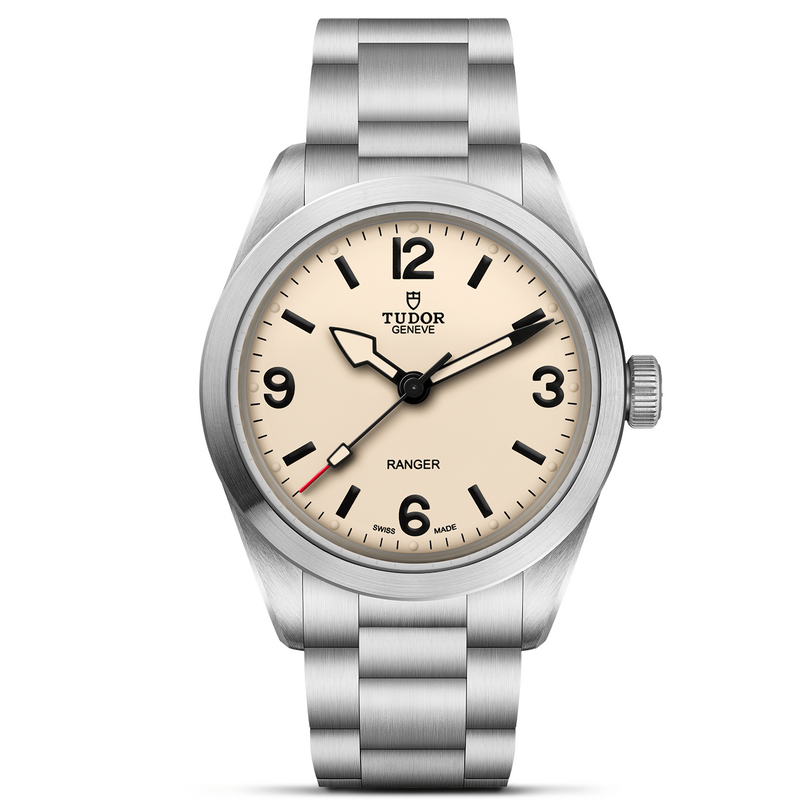 The TUDOR Ranger is an expedition watch with a stainless steel case, cream dial, black hour markers, prominent numerals at 3, 6, 9, and 12, sword-shaped hands, and a brushed metal bracelet for rugged style.