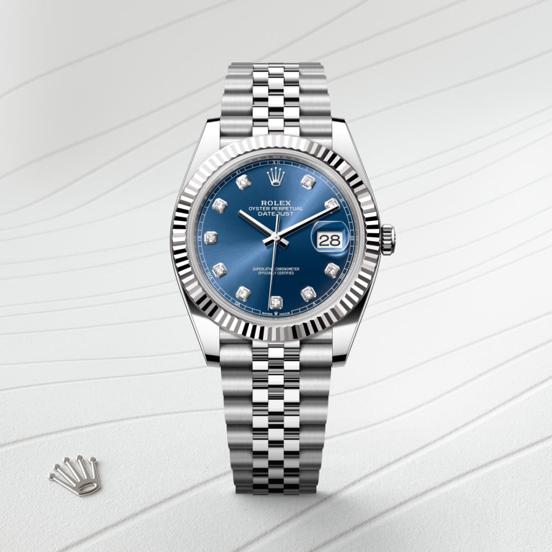 A silver Rolex watch with a blue dial and diamond hour markers on a textured white background.