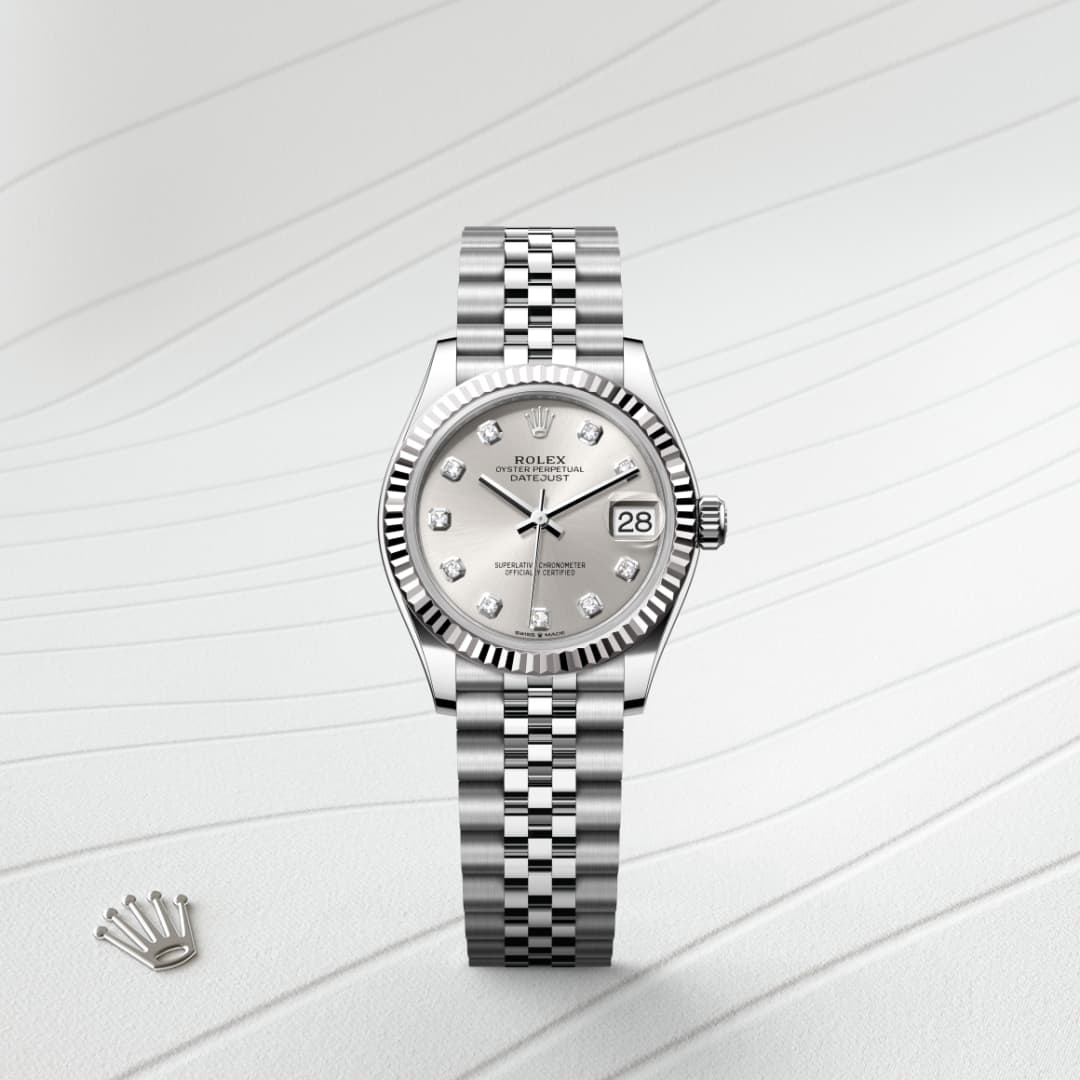 A silver Rolex watch with a diamond-studded dial and date display, placed on a textured white surface.