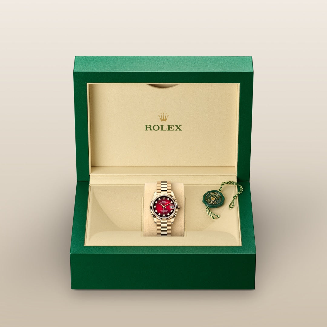 A Rolex watch with a red dial in a green and beige Rolex box with a green tag.