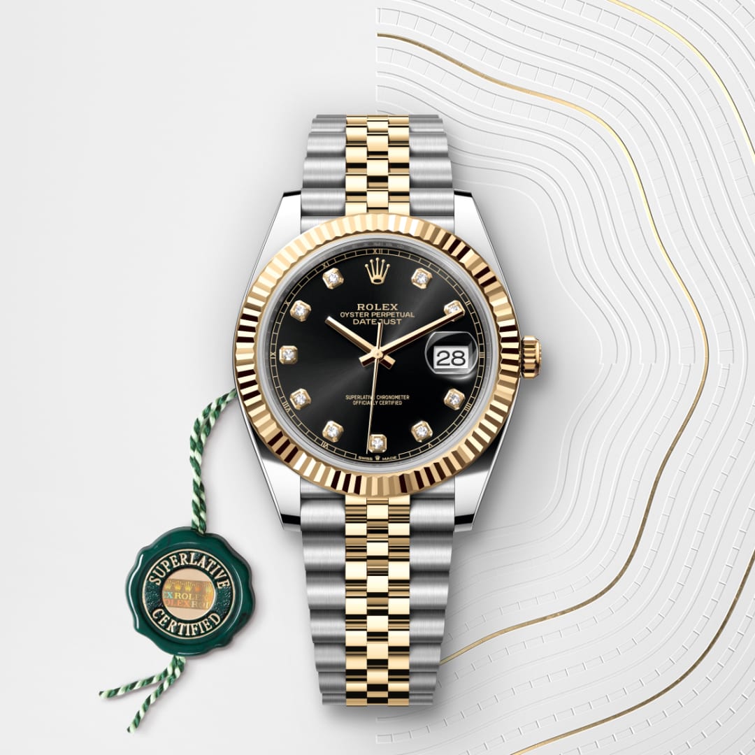 A Rolex Datejust watch with a black dial, gold accents, and a two-tone bracelet displayed on a patterned surface.