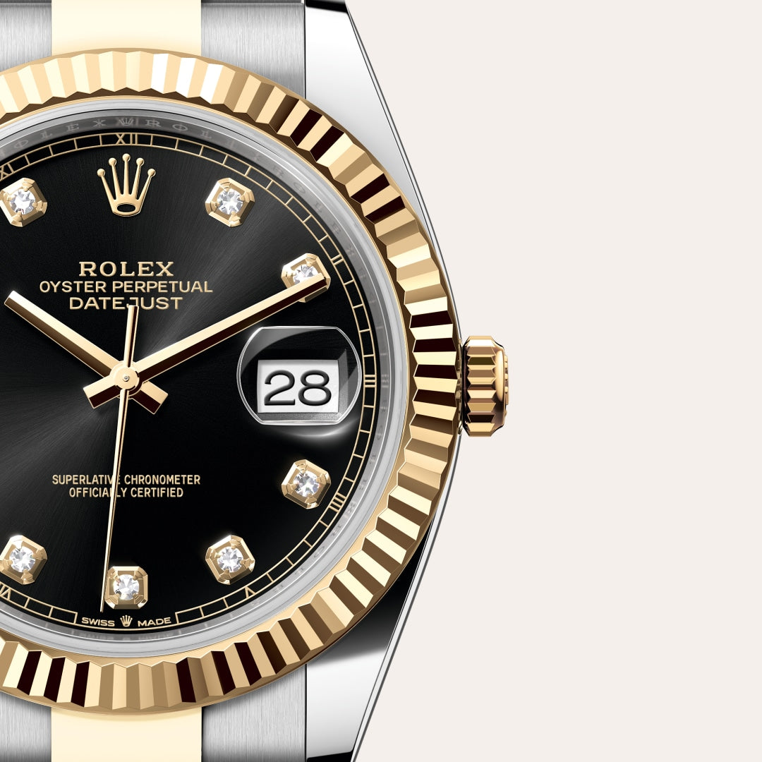 Close-up of a Rolex Datejust watch with a black dial, gold bezel, and diamond hour markers showing the date 28.