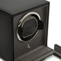 Black watch winder with single rotating cushioned cradle, silver-tone ring, and protective cover, front view.