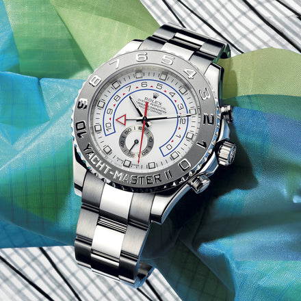 Rolex Yacht-Master II watch with a silver and white face on a multicolored cloth background.