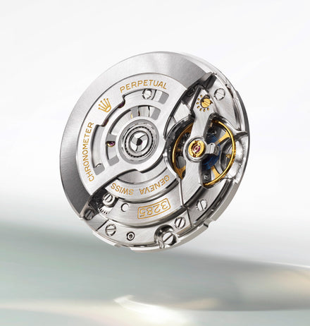 Close-up of a Rolex watch movement with visible gears, engravings, and gold accents.