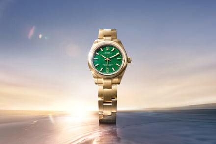 Gold watch with a green face on a blurred landscape background