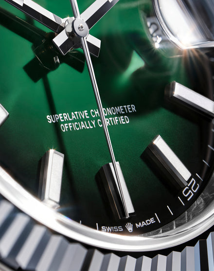 Close-up of a Rolex watch face with green dial and silver accents.