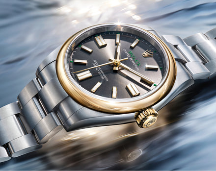 Luxury watch with silver and gold band on water background