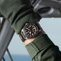 Close-up of a wrist wearing a watch with a blurred outdoor background