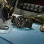 Watch with green strap on a map with military equipment in the background